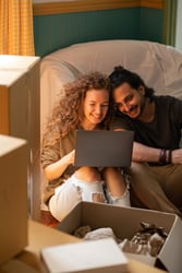 happy-diverse-couple-using-laptop-while-relocating-into-new-4247819